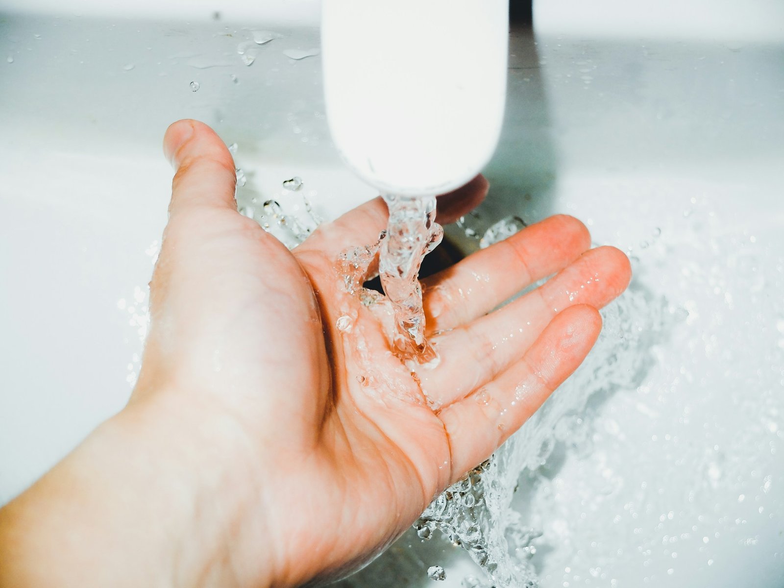 Hand prüft einen Wasserhahn am Waschbecken nach der Reinigung